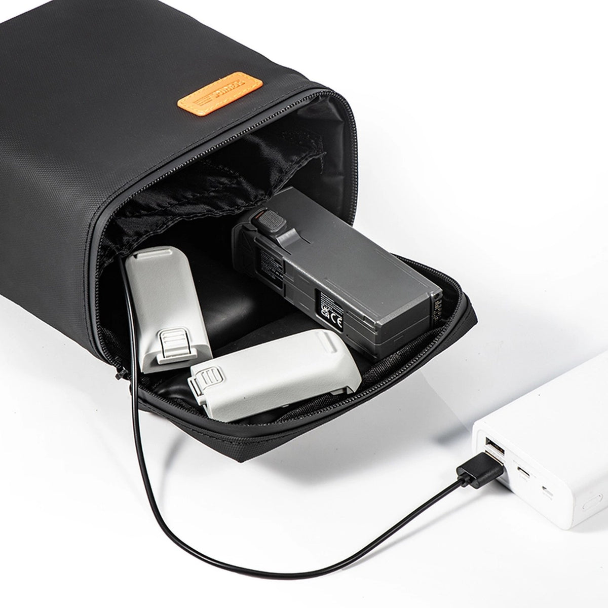 STARTRC Akku-Heiztasche geöffnet mit DJI-Akkus, per USB an einer Powerbank