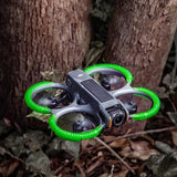DJI Avata 2 mit STARTRC Anti-Kollisionsringen im Flug vor Baumstämmen